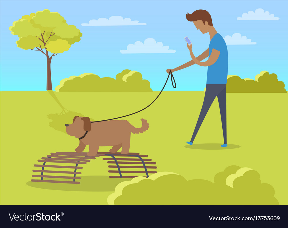 Young boy walking with dog and using phone in park