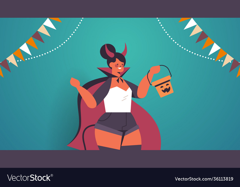 Girl in devil costume holding bucket with pumpkin