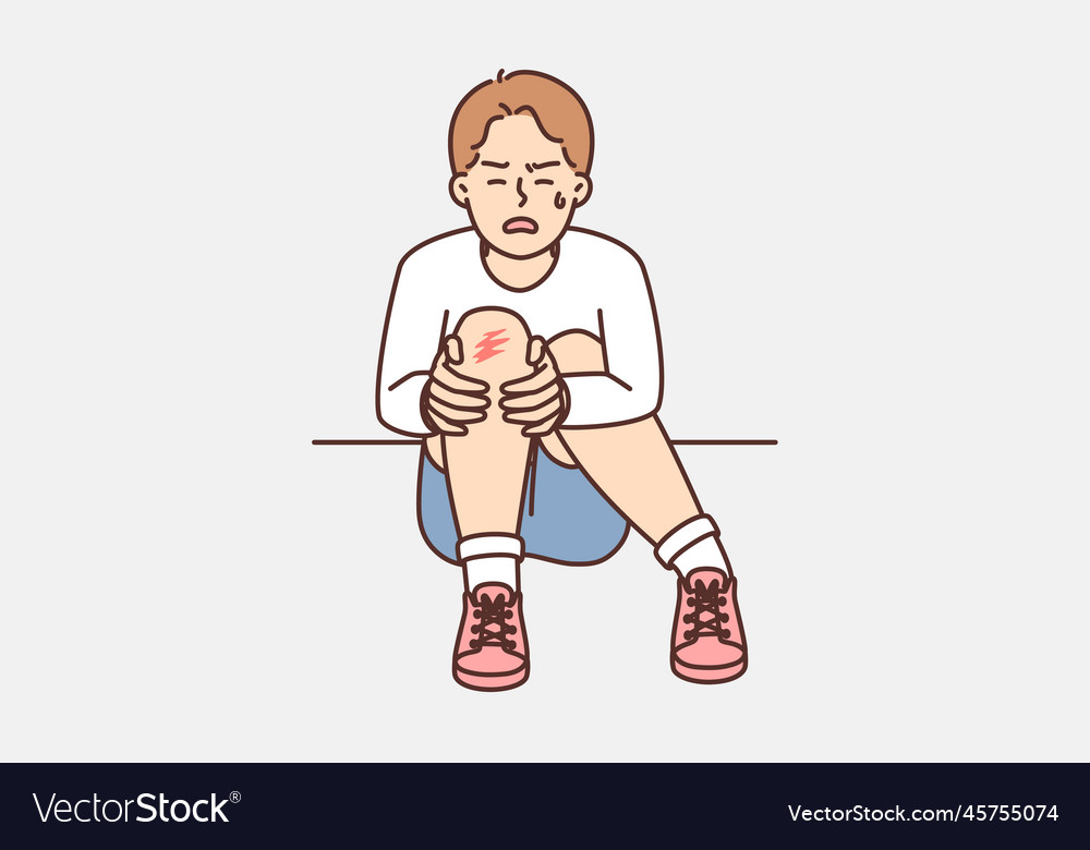 Crying boy sits on ground and holds to injury Vector Image