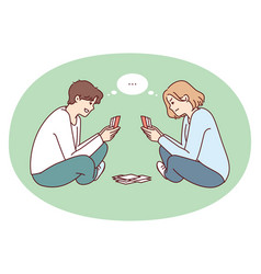 Young Man And Woman Play Cards Sitting On Floor