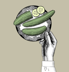 Female Hand Holding A Plate With Green Cucumbers