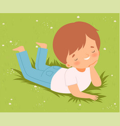 Smiling Boy Lying Down On Green Lawn On His