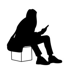 Woman Sitting On Box Looking At Mobile Phone